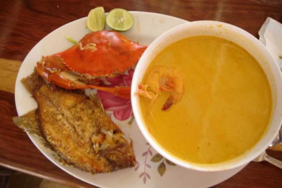 Un plato de pescado junto a un cuenco de sopa.