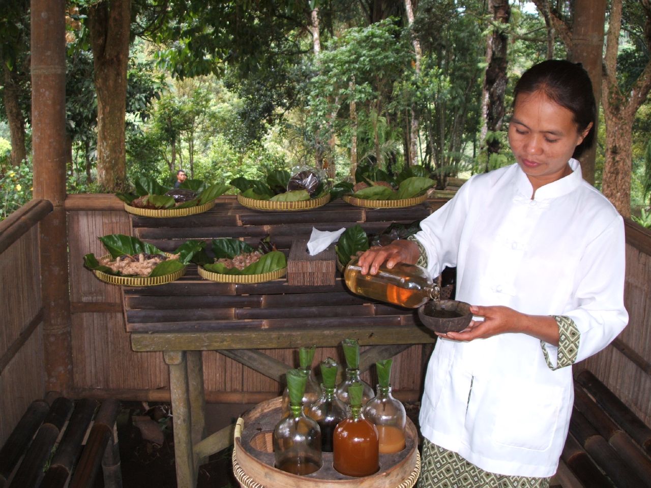 Una vendedora sirve una bebida en un puesto de jamu.
