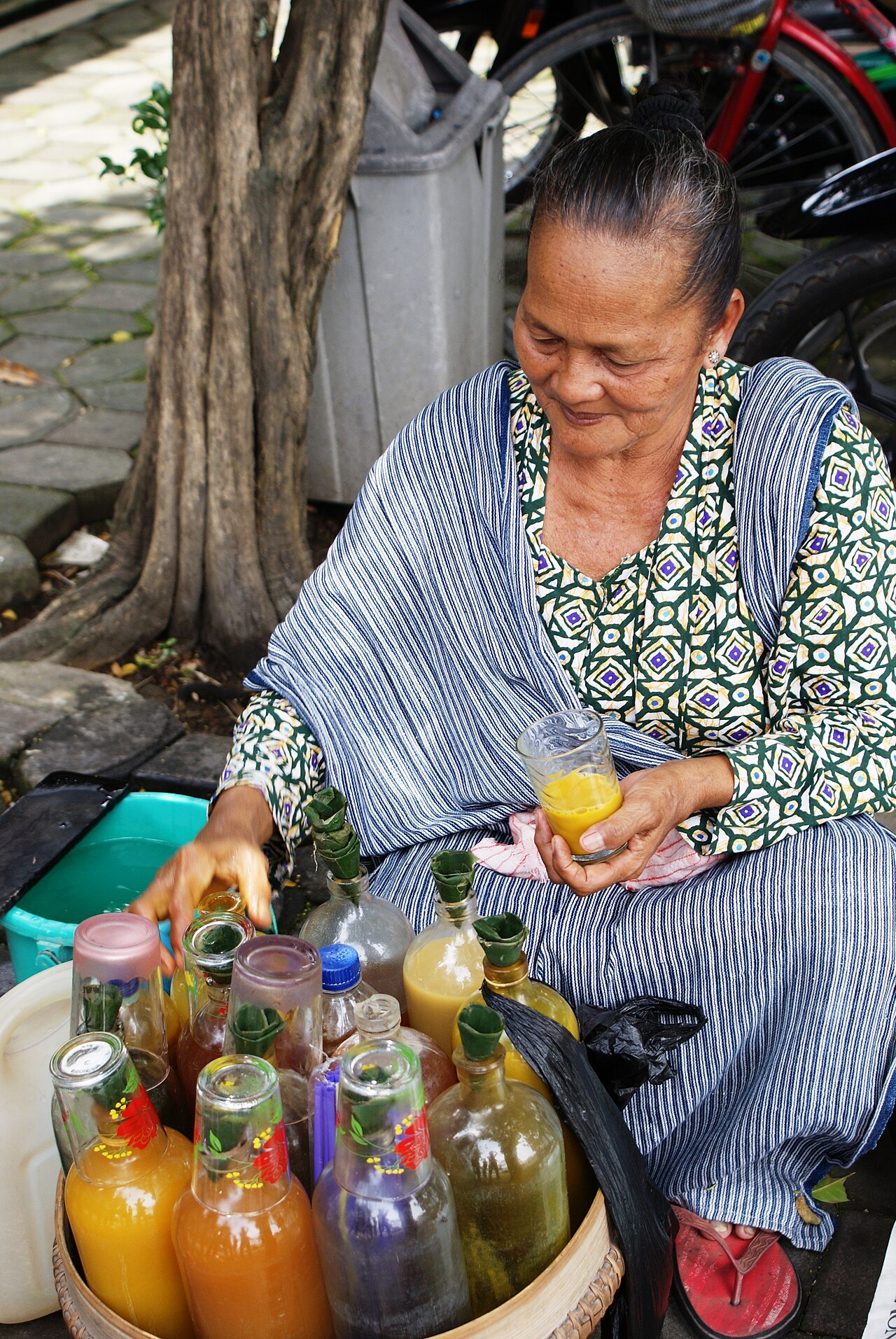 Una vendedora de jamu y sus botellas.