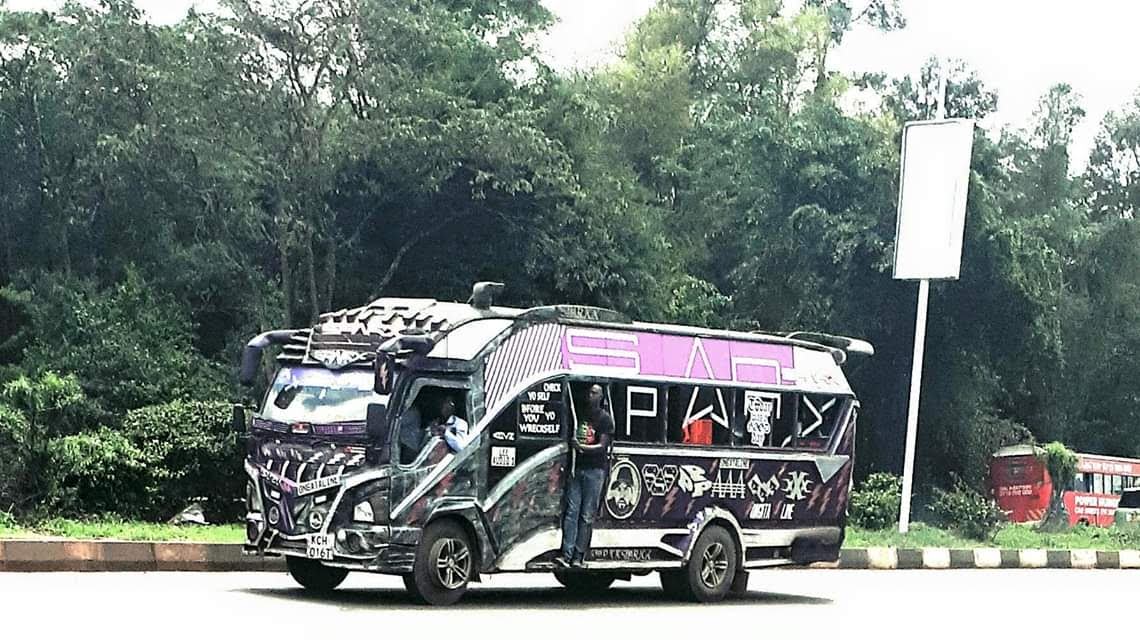 路上一辆装饰过的Sparxx小巴，售票员站在敞开的车门处。