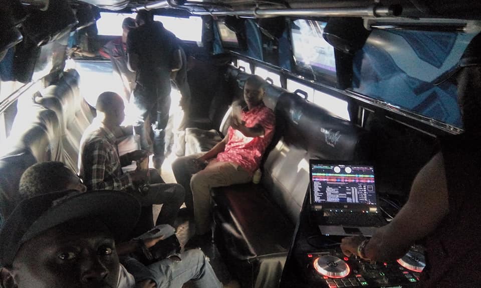 People seated inside a customised minibus beside a laptop and DJ controller.