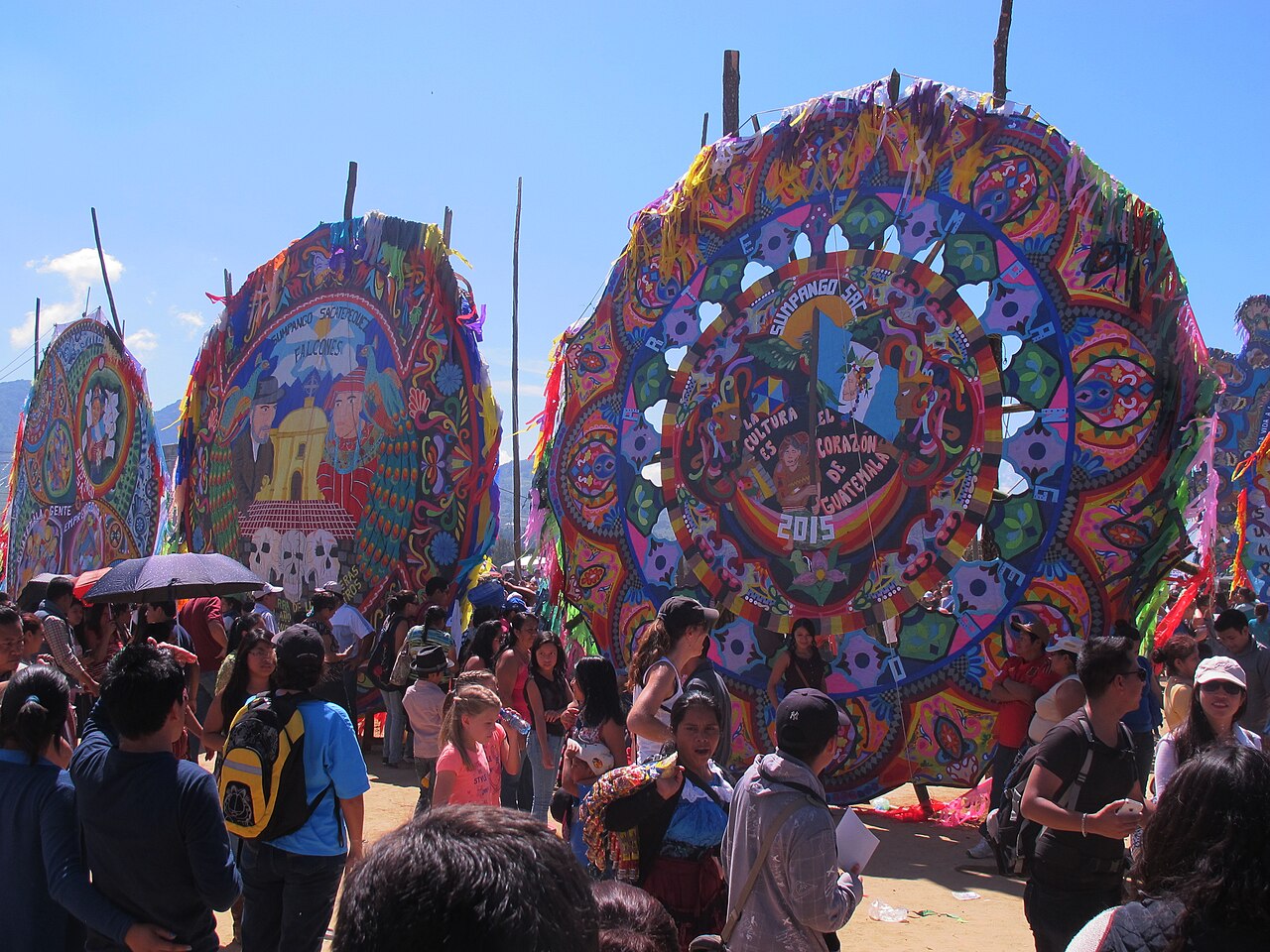 Une foule sous des cerfs-volants colorés et une banderole sur la culture guatémaltèque.