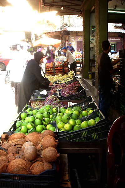 Un étal de fruits et légumes avec des clients.